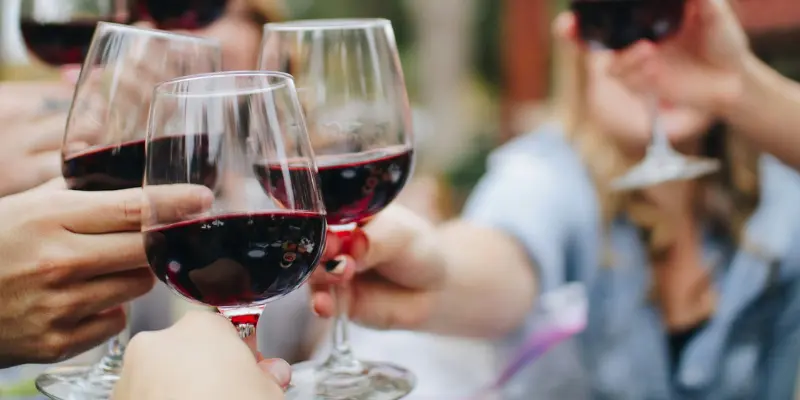 Group of people toasting with glasses of red wine at a social gathering