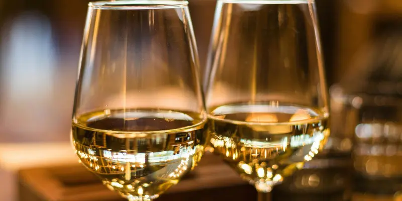 Close-up of two glasses filled with white wine in a warmly lit setting